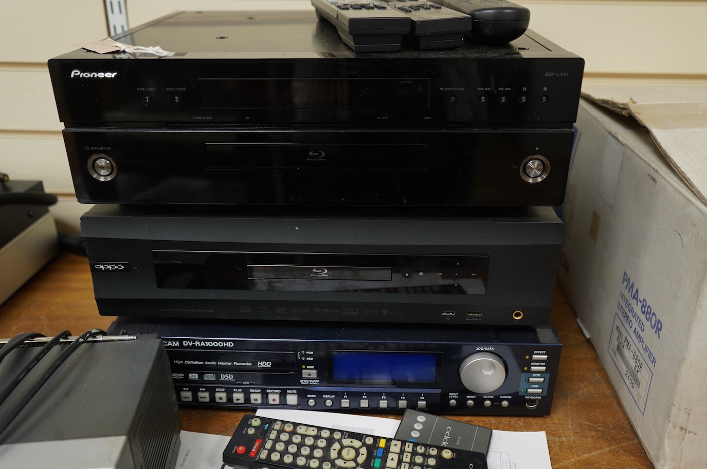 Three Blu-ray/DVD players including; an OPPO BDP-105EU Blu-ray player with user manual and remote control, a Pioneer BDP-LX91 Blu-ray player with remote control, and a Tascam DV-RA1000HD DVD player with owners manual, bu